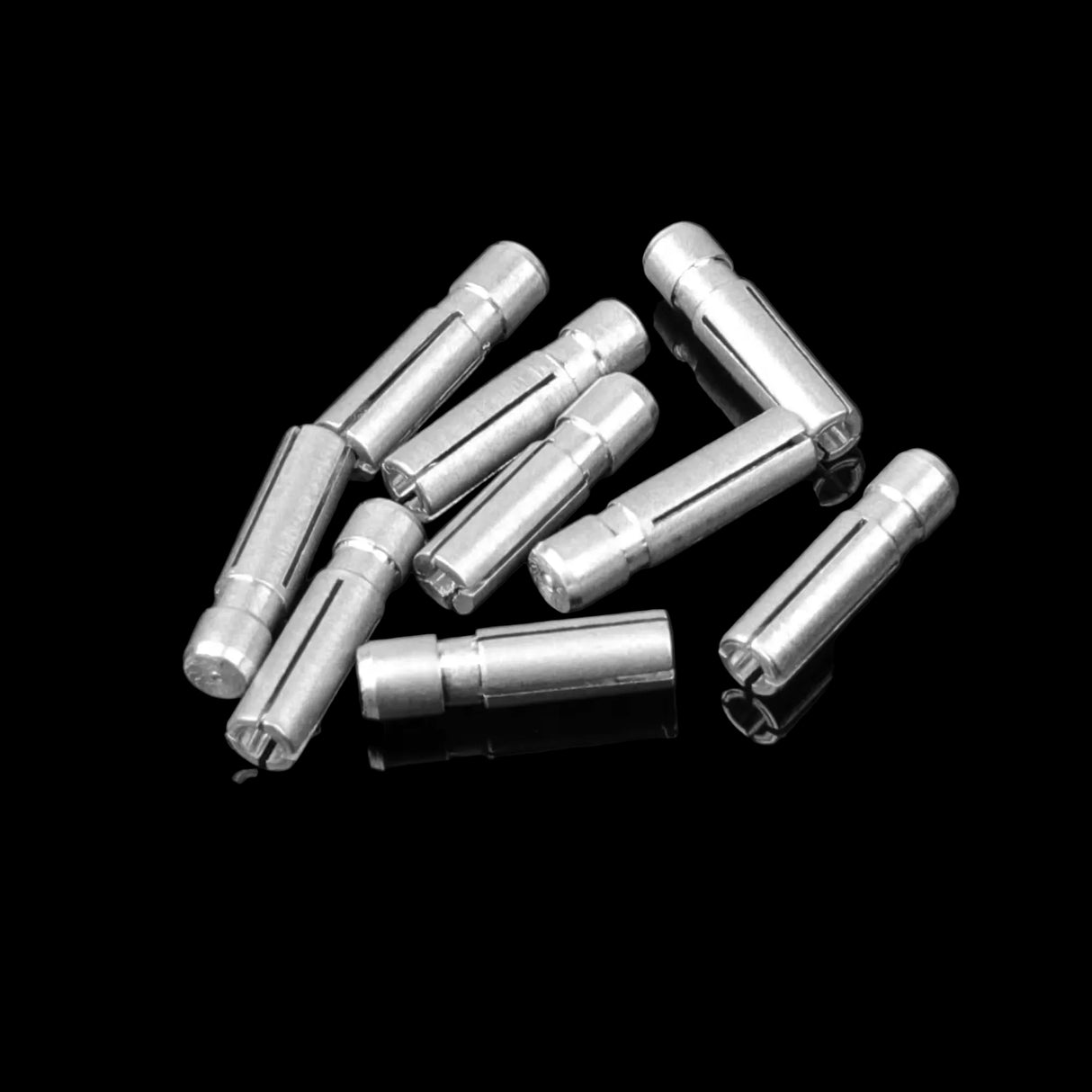 A collection of silver dart flight protectors scattered on a dark surface.